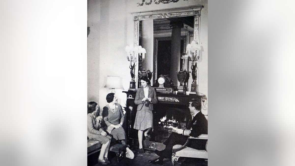 A black and white photo of a young Queen Elizabeth with her parents and sister at Royal Lodge