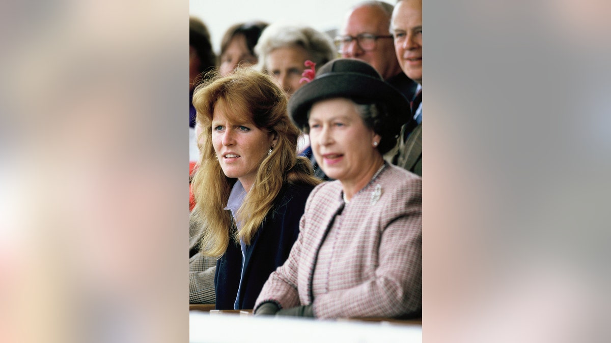 Sarah Ferguson standing next to Queen Elizabeth in the middle of an audience