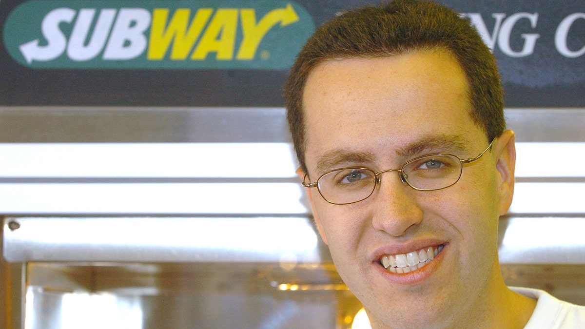 Jared Fogle smiing next to a Subway logo