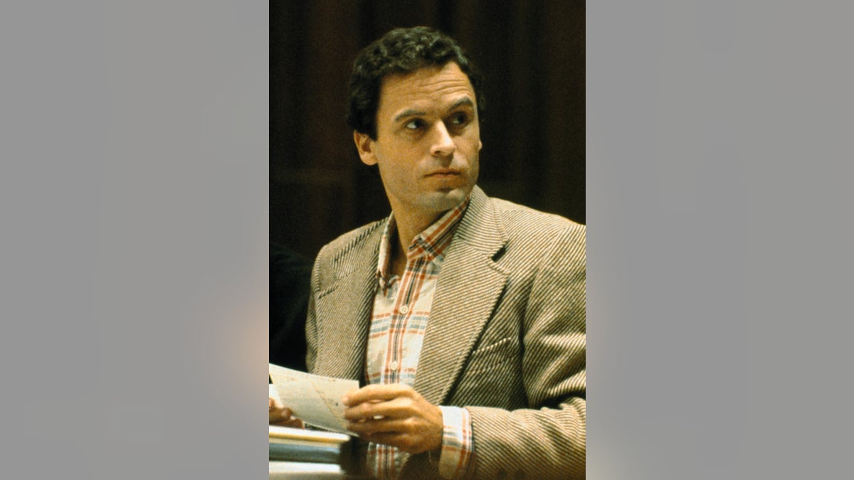 Ted Bundy wearing a blazer and a plaid shirt looking away from the camera