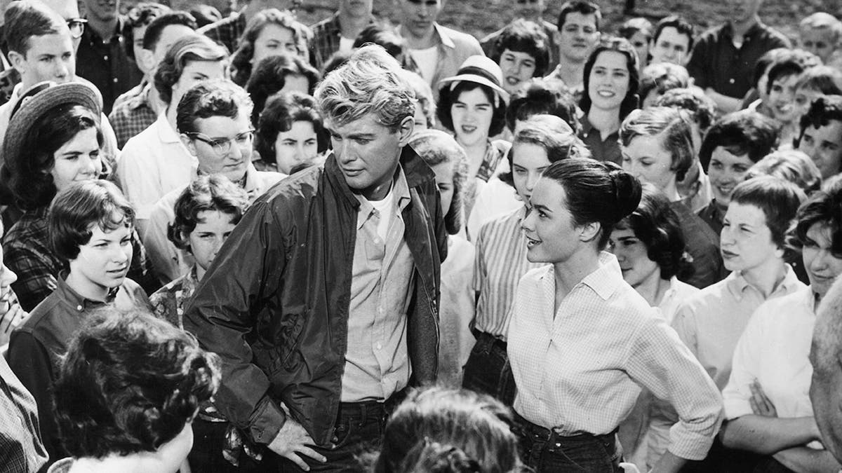 Troy Donahue being surrounded by women in a black and white photo