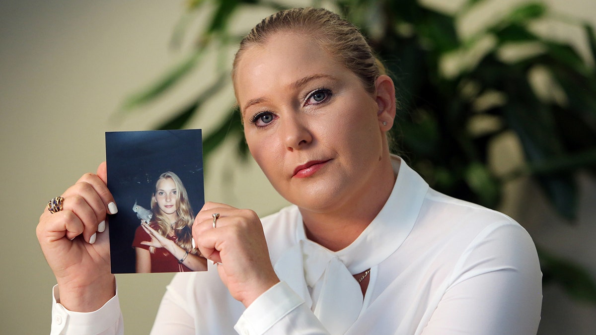 Virginia Giuffre wearing a white sweater and holding a photo of her younger self