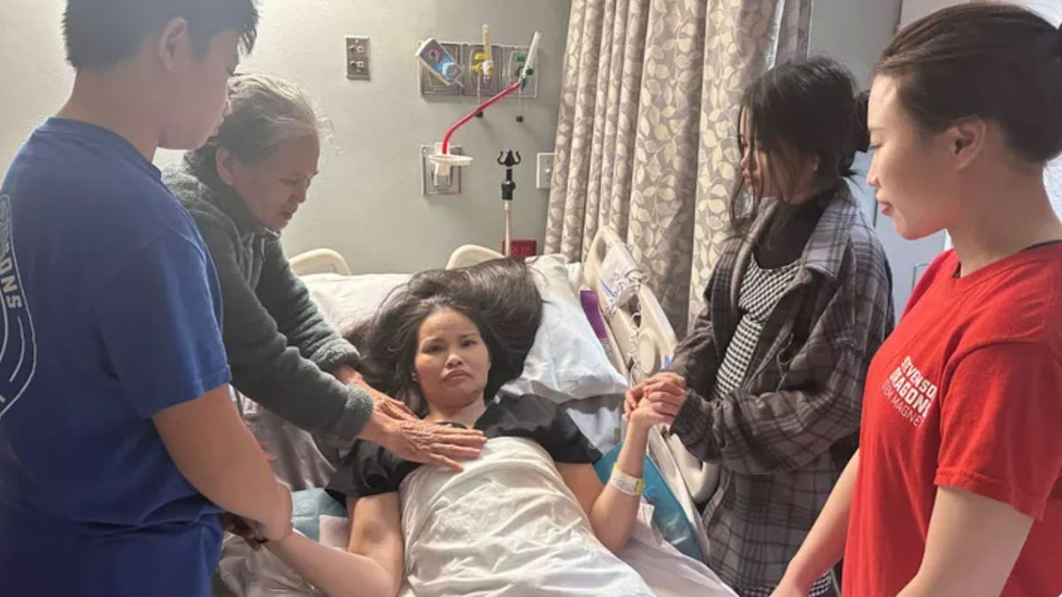 Woman in hospital bed with her family.