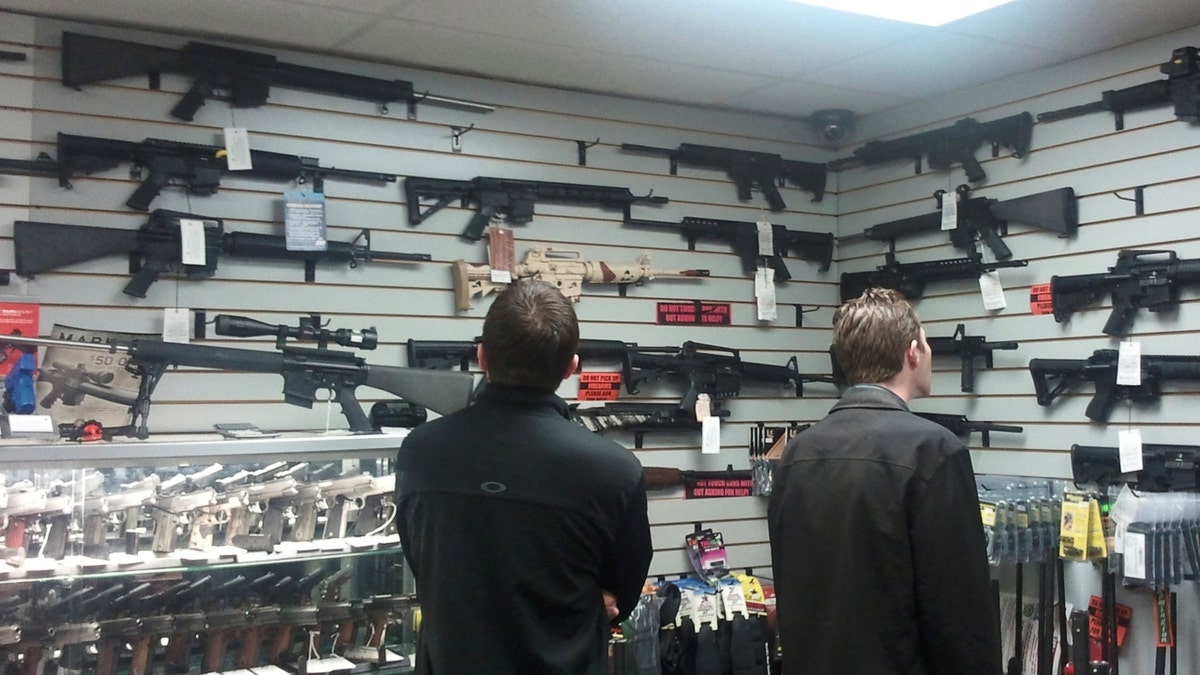 customers look at guns displayed on walls of gun store