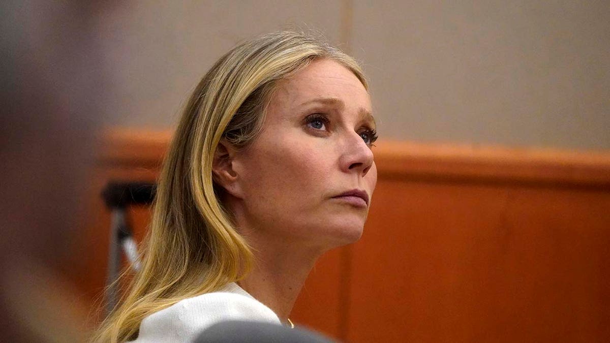 Gwyneth Paltrow sits in court wearing white coat