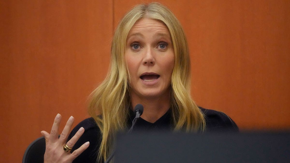 Gwyneth Paltrow takes the stand in ski accident trial in a blue dress with her hand up, in a passionate way, as if to emphasize something