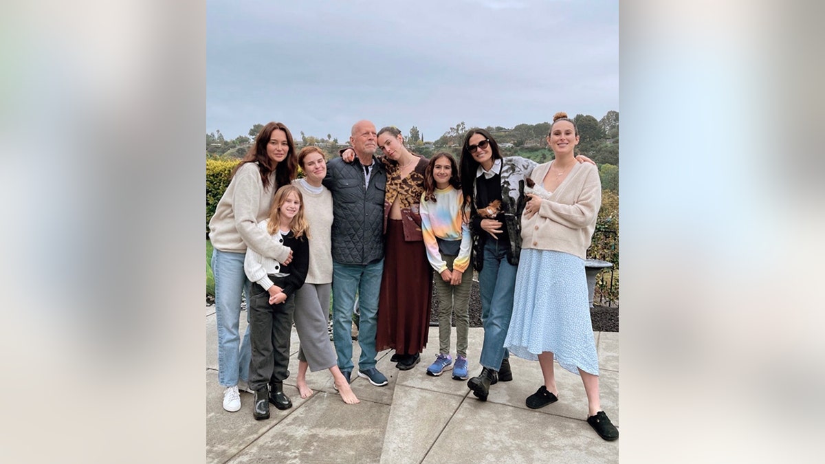 Bruce Willis is surrounded by his family outside on the patio for his birthday, from left: Emma, ​​Evelyn, Tallulah, Bruce, Scout, Mabel, Demi and Rumer