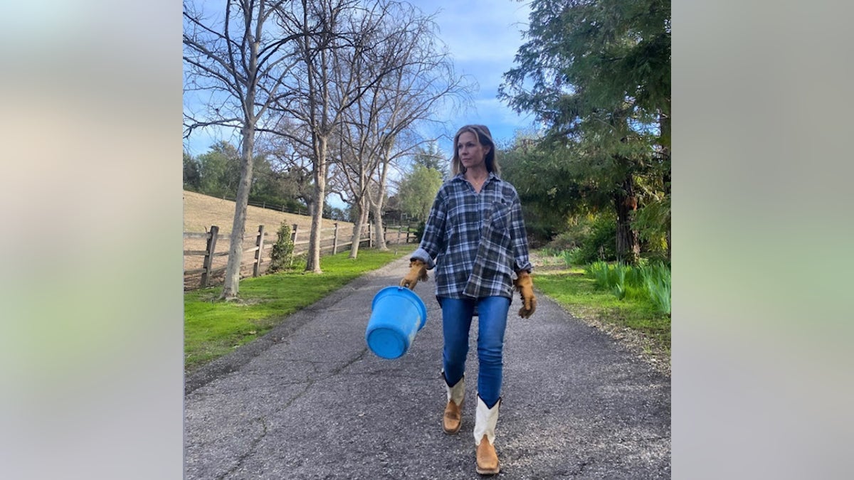 jennie carrying pail and walking on a country road