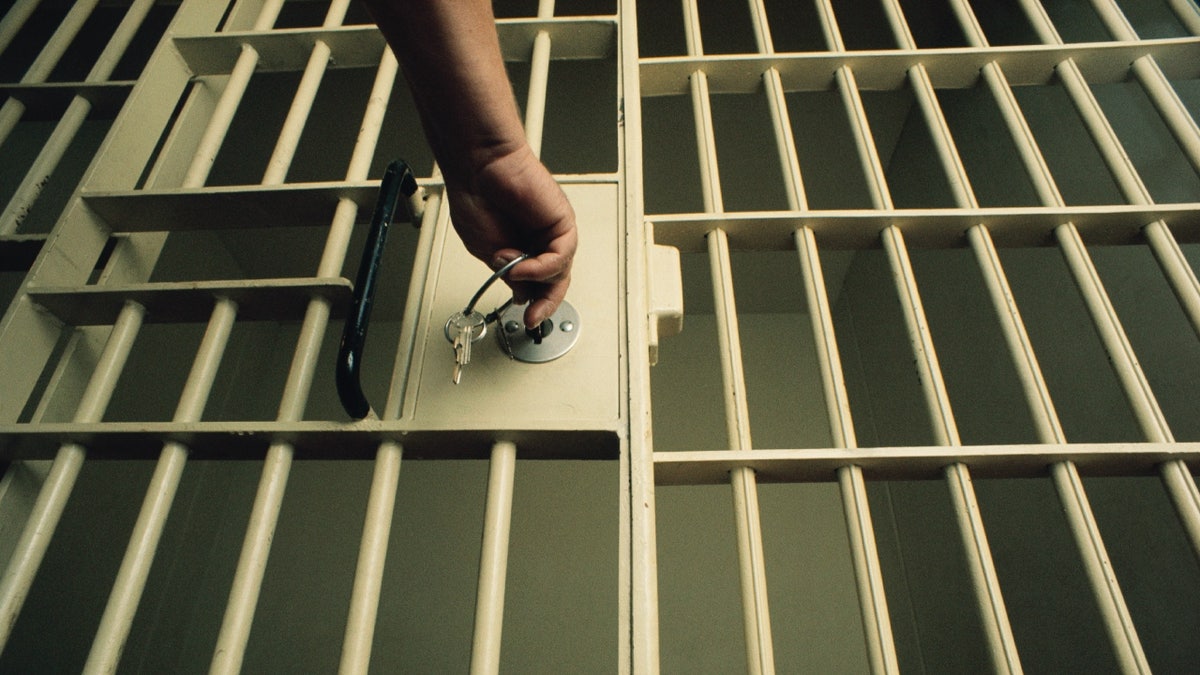 Stock image of guard locking jail cell with key