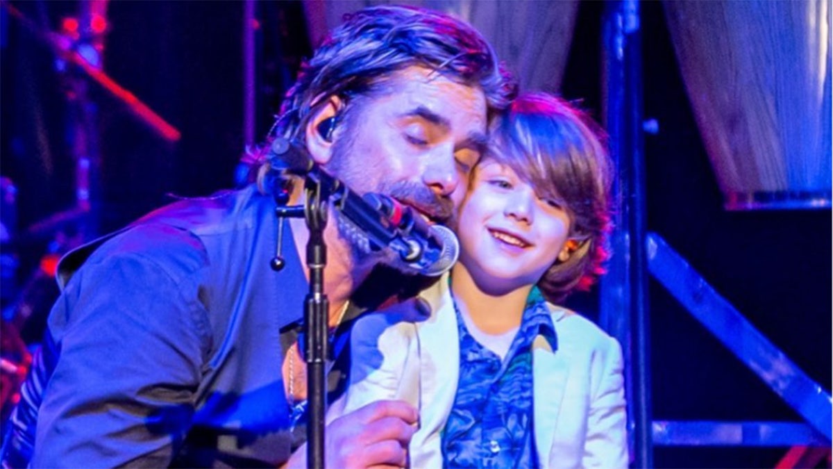John Stamos and his son on stage at a Beach Boys concert