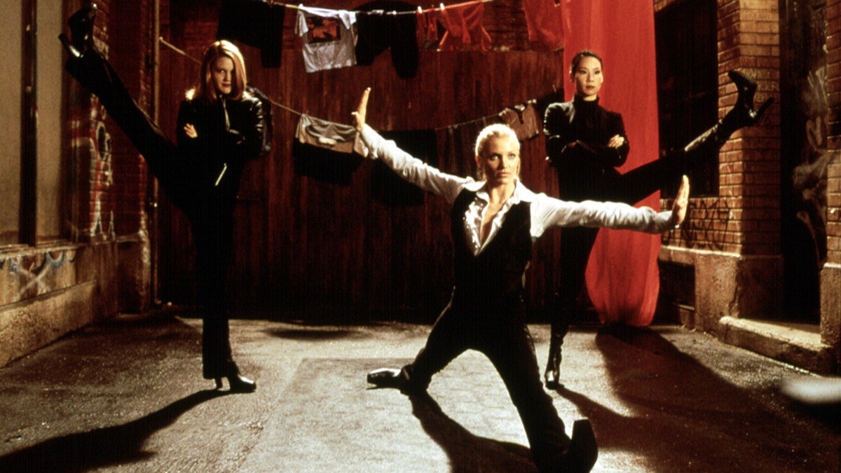 Drew Barrymore sticks her right leg up in the air, Cameron Diaz middle does a split and Lucy Liu kicks her left foot up in the air in a shot from "Charlie's Angels"