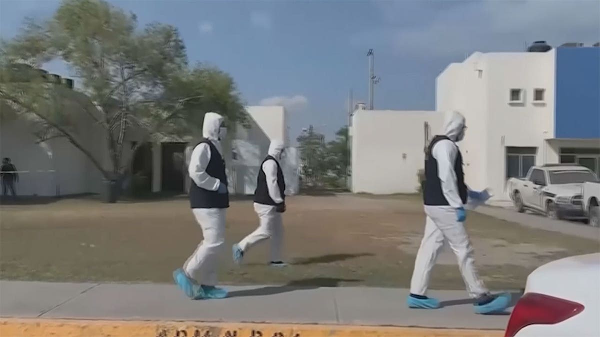 Medical professionals in hazmat suits walking down the stree.