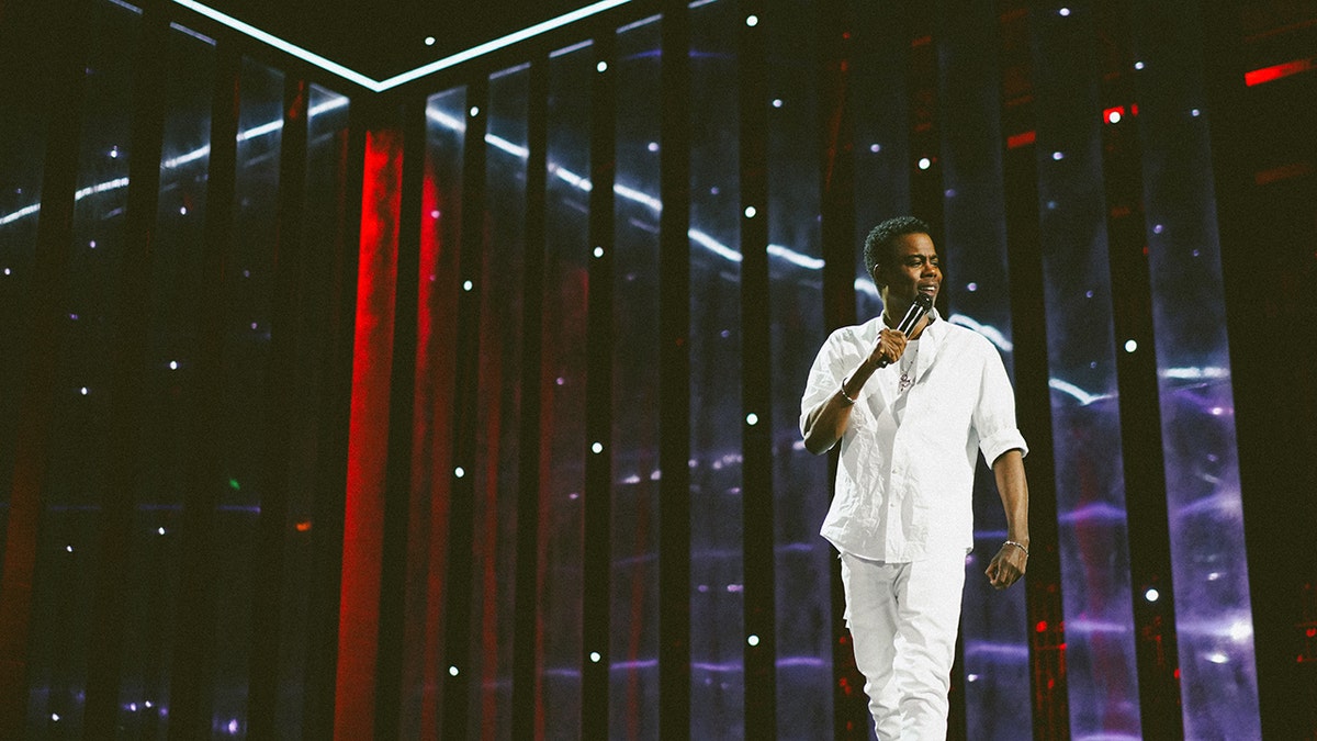Chris Rock wearing all white on stage doing stand-up