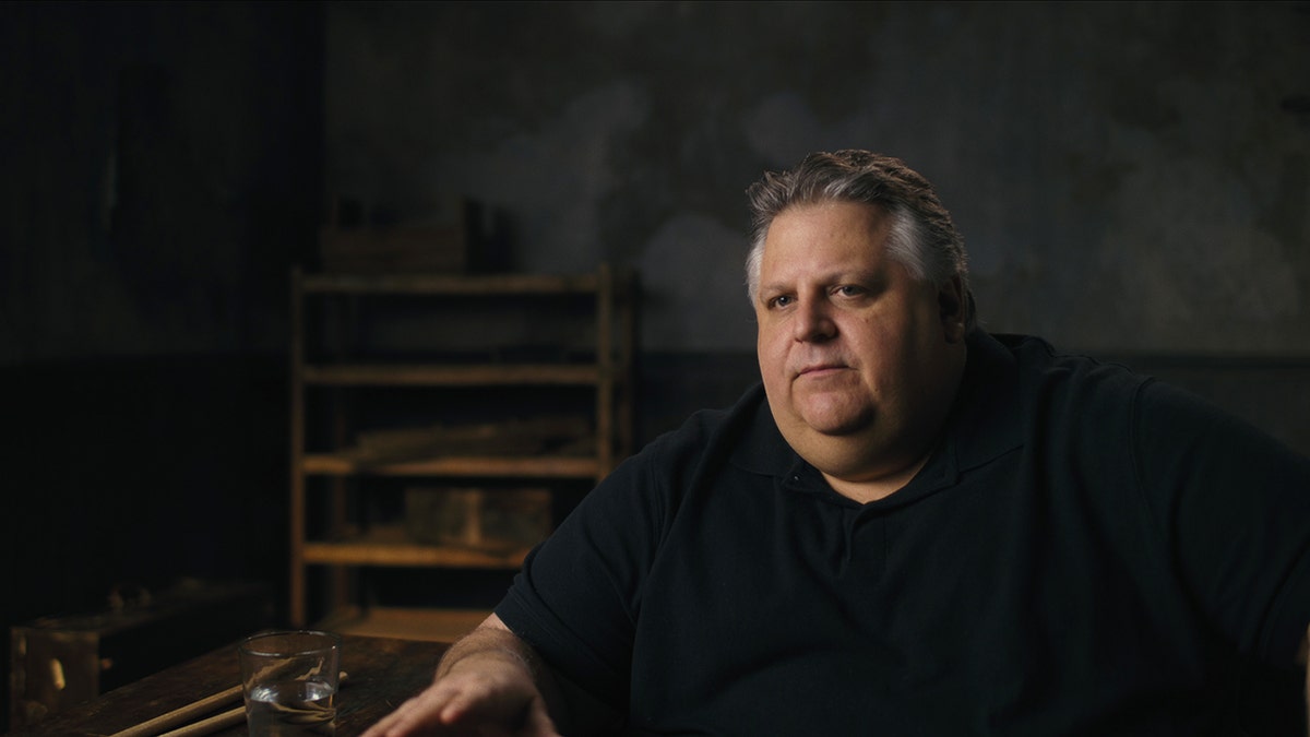 David Thibodeau wearing a black shirt sitting in front of a table