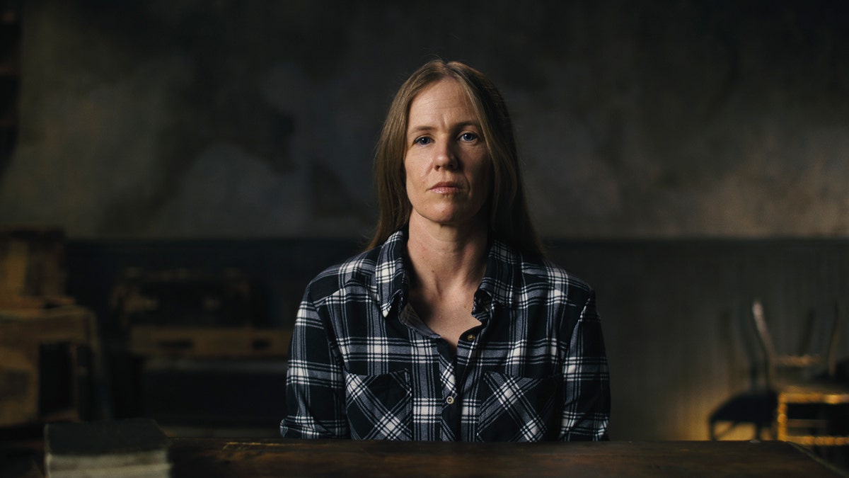 Heather Jones wearing a plaid shirt sitting in front of a table