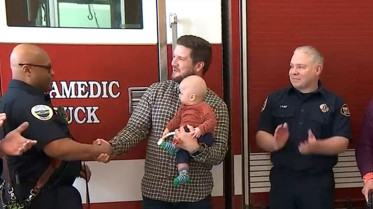Ronnie Coulam, holding infant shaking firefighter's hand