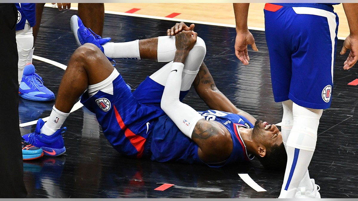 Paul George holds knee in pain