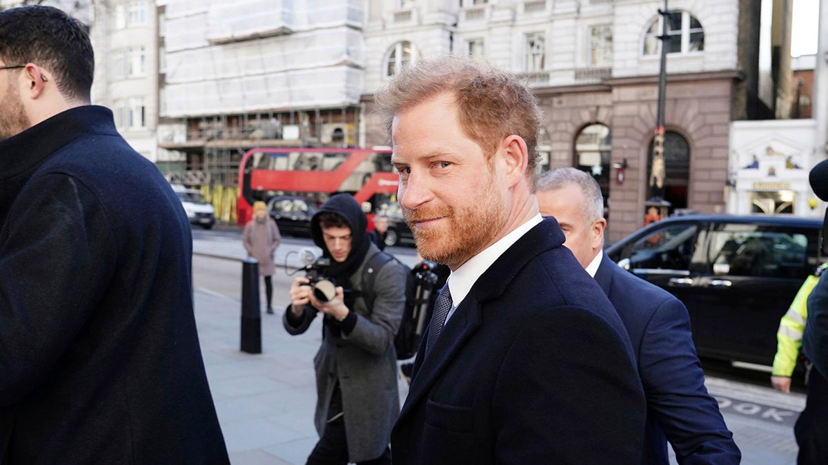 Prince Harry smiles as he arrives in court.