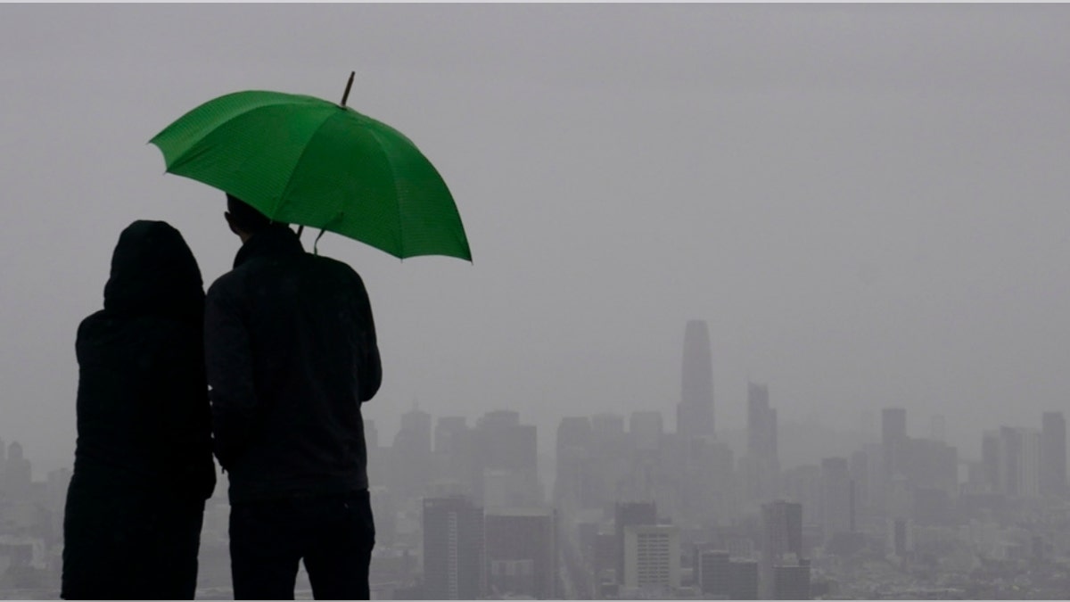 People stand under an umbrella in San Francisco, Calif.