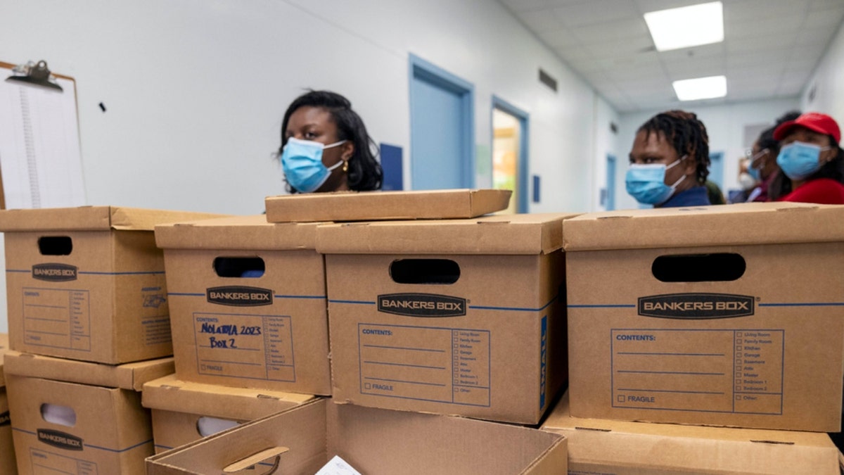 People stand around boxes filled with recall petitions for New Orleans Mayor LaToya Cantrell