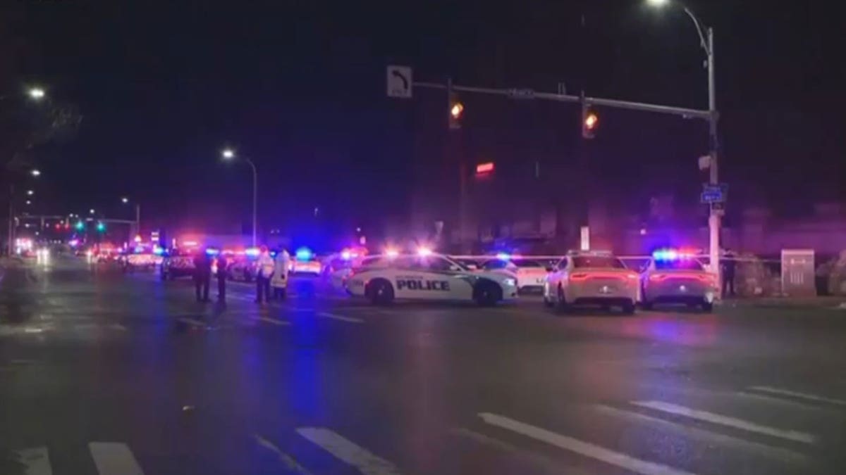 Police blocking a street with caution tape and police units.