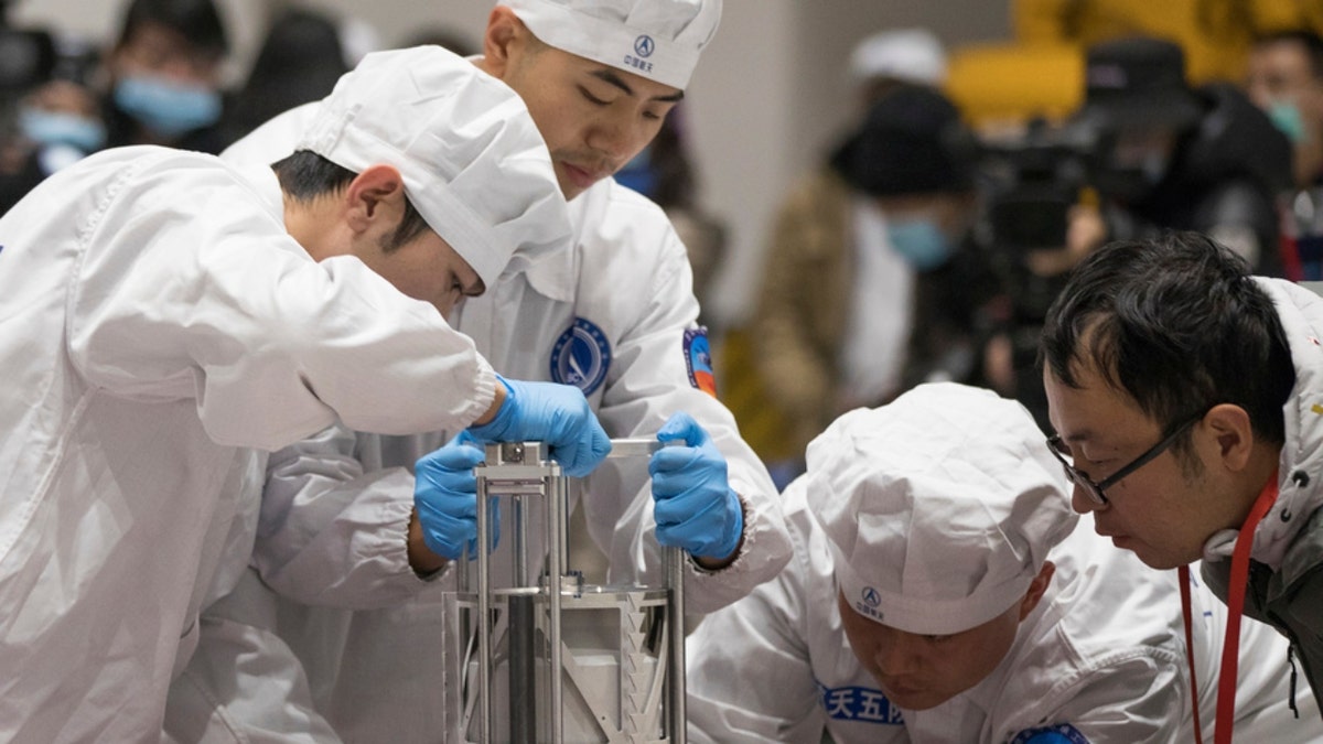 Chinese scientists prepare to weigh a container carrying moon samples