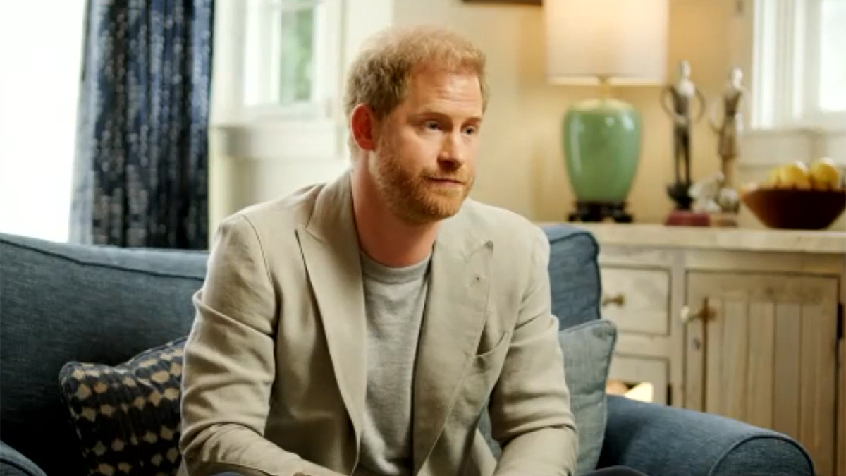 Prince Harry wears beige blazer while sitting on blue couch to discuss trauma therapy about psychedelics