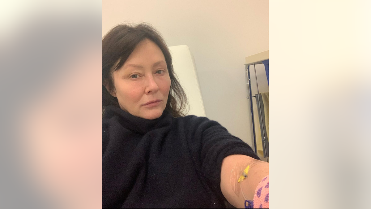 Shannen Doherty wears black turtleneck with an IV in her arm