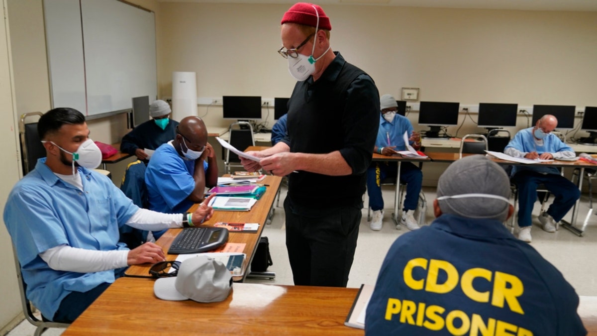Instructor Douglas Arnwine hands back papers with comments to his incarcerated students at San Quentin