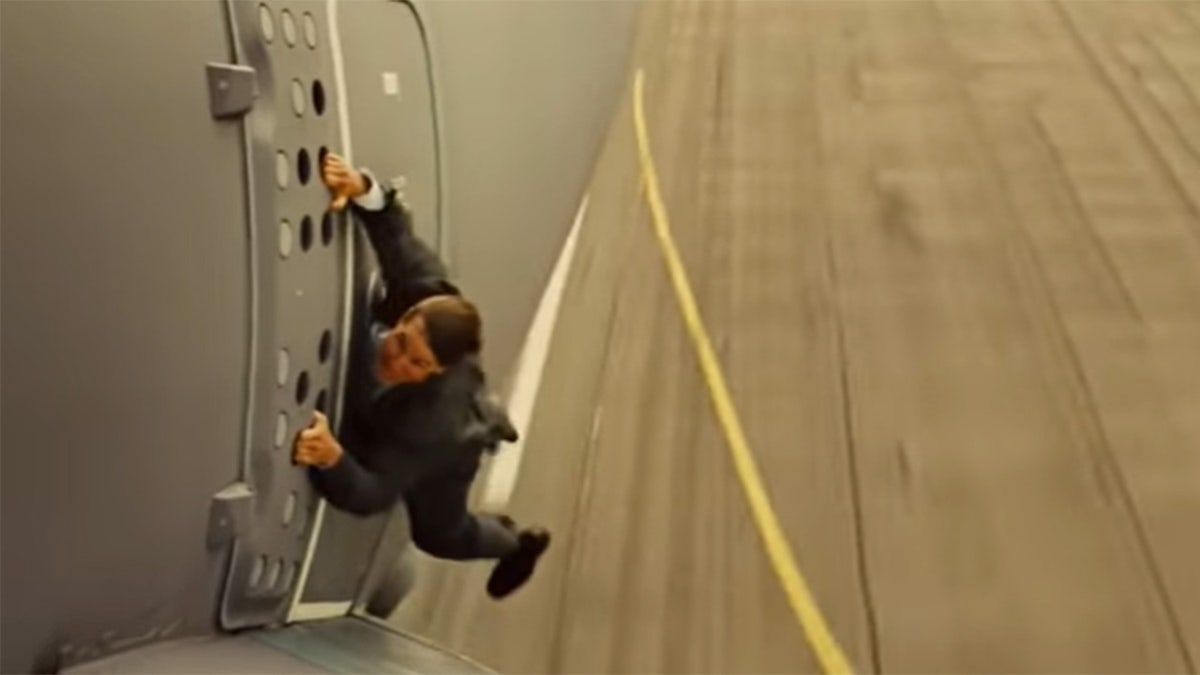 Tom Cruise hanging off the side of a plane in a stunt for Mission Impossible Rogue Nation