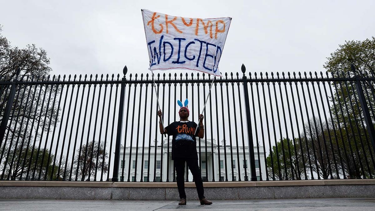 Nadine Seiler holds a "Trump Indicted" sign in front of the White House after former U.S. President Donald Trump's indictment