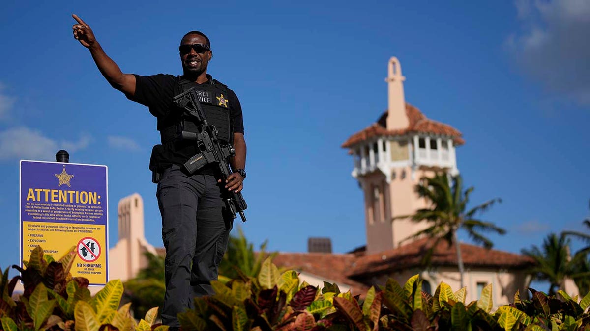 A secret service agent tells passerby to keep moving, as he stands guard on the wall surrounding former President Donald Trumps Mar-a-Lago estate
