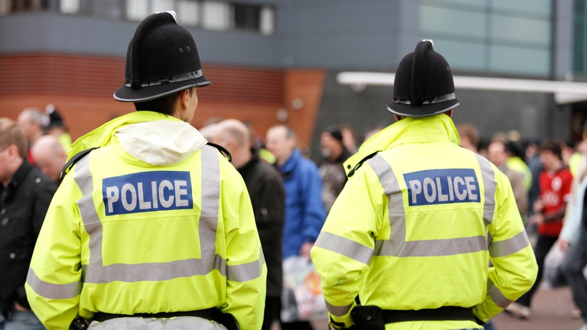 British bobbies in bright yellow POLICE vests seen from behind