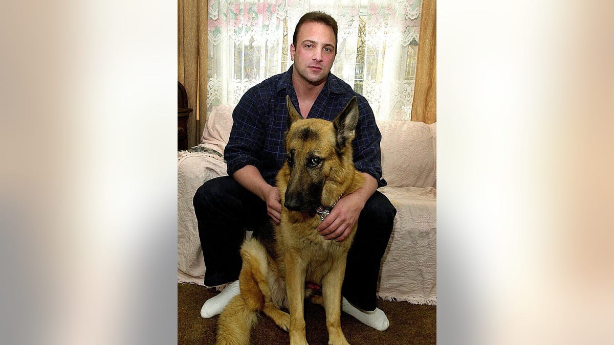 Nick Tartaglione poses with his German Shephard dog.