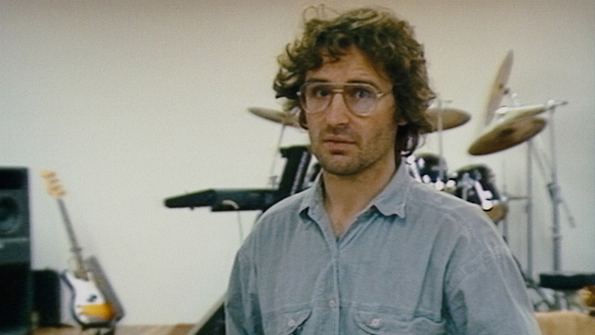 David Koresh wearing a powder blue shirt in front of a drum set