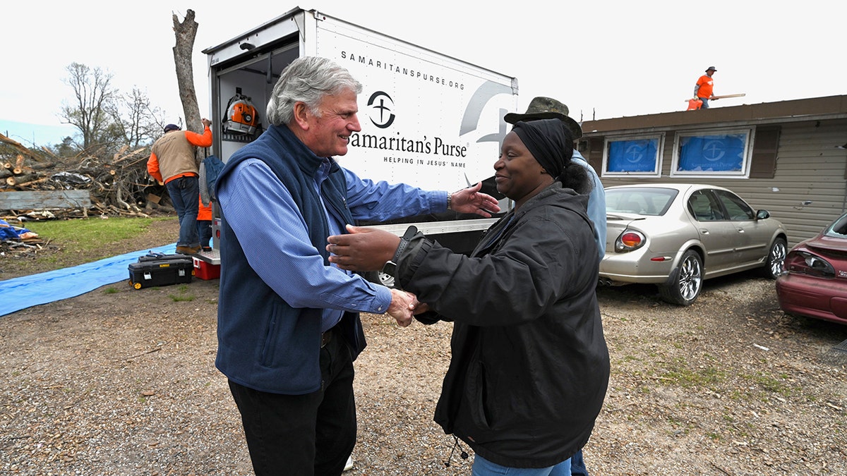 Franklin Graham with a Samaritan's Purse truck. He's shaking hands with people.