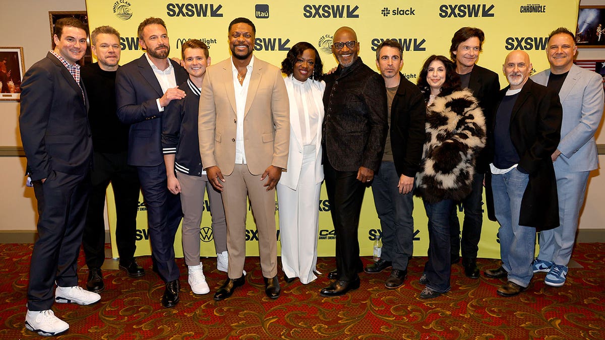 Cast of "Air" smiles in front of yellow banner during movie premiere