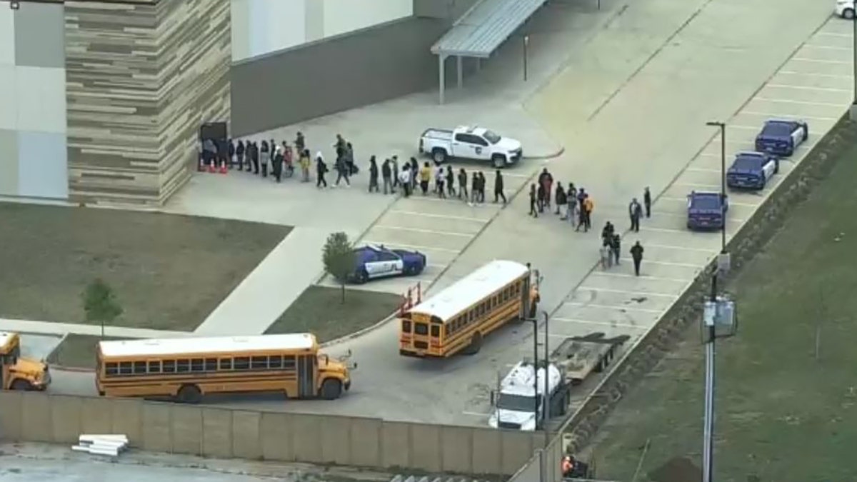 school buses and students walking in a line into a building