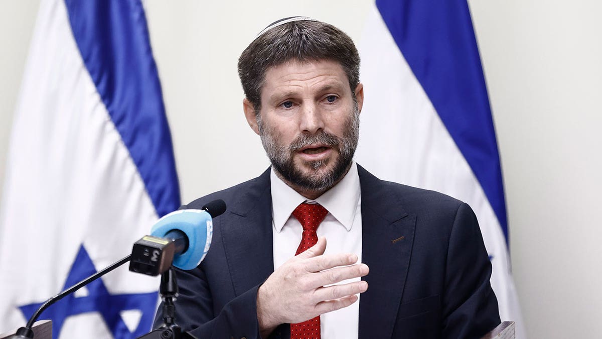 Bezalel Smotrich speaks into a microphone at a podium 