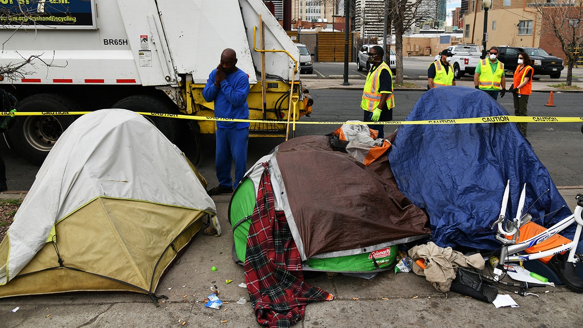 A garbage truck parks near a line of tents in Denver, Colorado