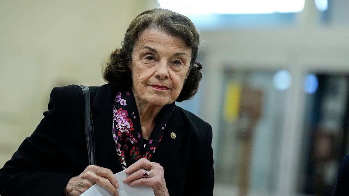 Sen. Dianne Feinstein holds papers as she walks through Senate Subway