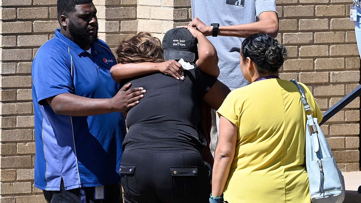 Parents comfort each other as they wait outside the Woodmont Baptist Church for students from Covenant School