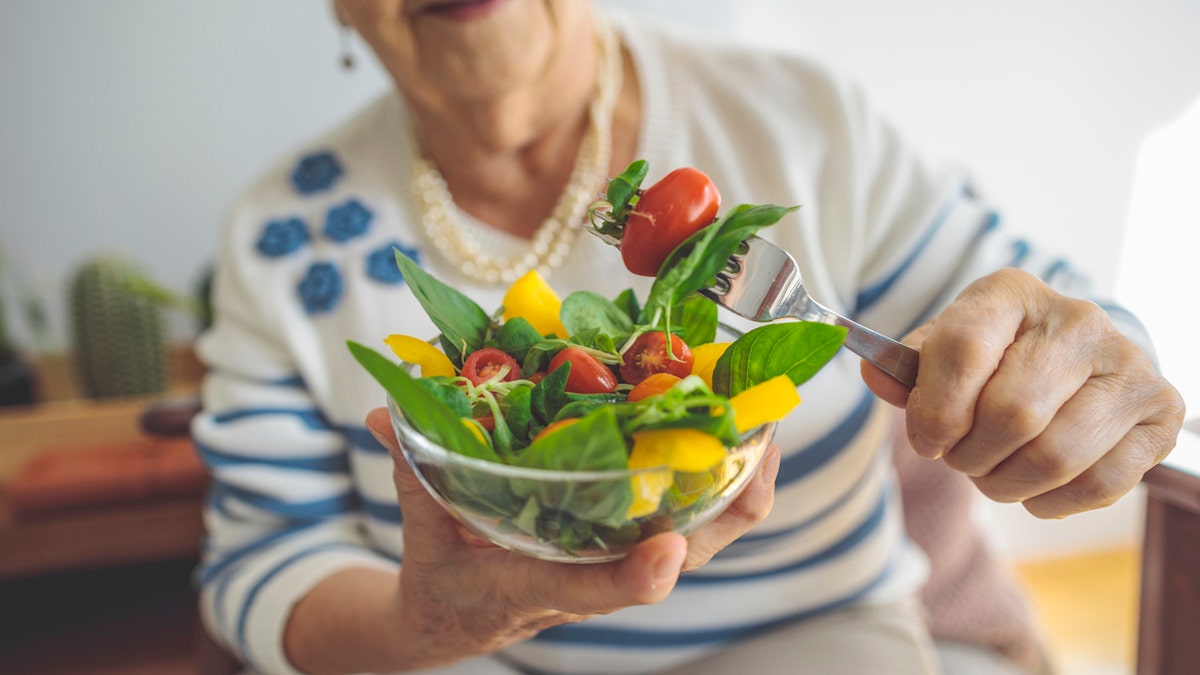 Elderly woman eating salad