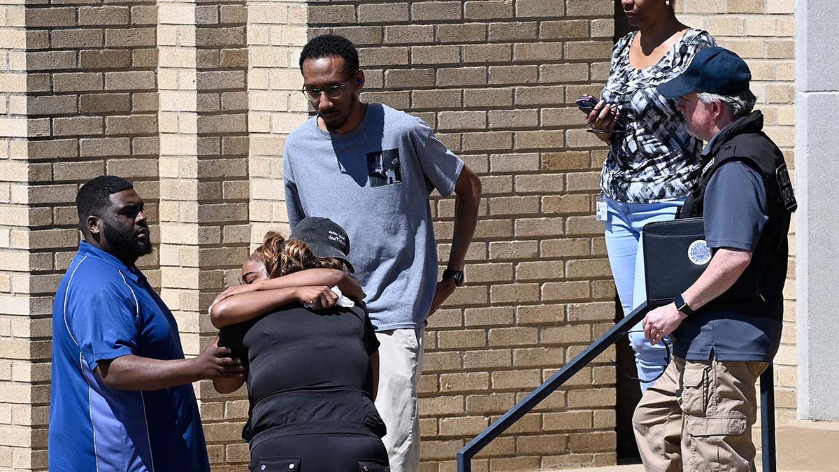 Parents comfort each other as they wait outside the Woodmont Baptist Church for students from Covenant School