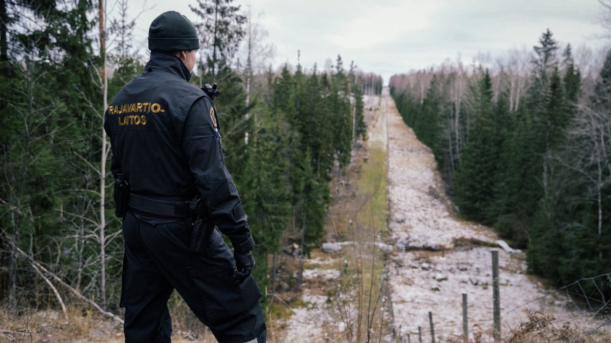 Senior border guard officer Juho Pellinen looks at a fence marking the boundary area between Finland and the Russian Federation