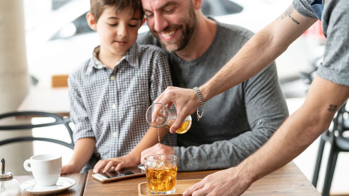 Server pours iced tea for son and father