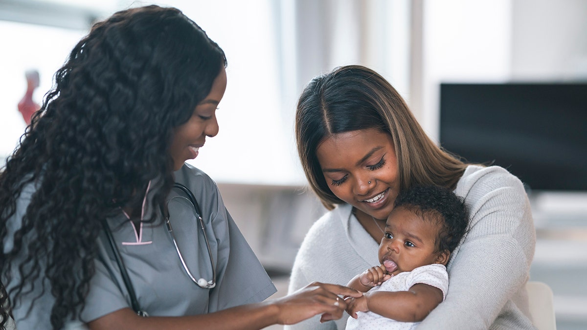 two women hold baby