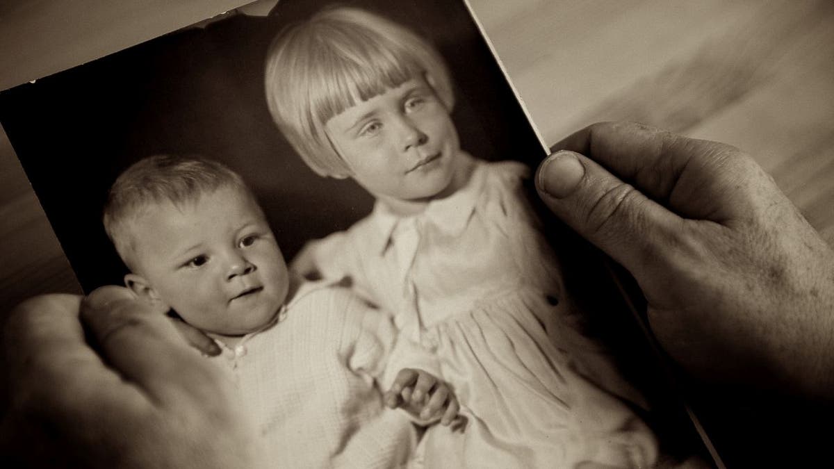 Person holds up photo of kids from 1920s