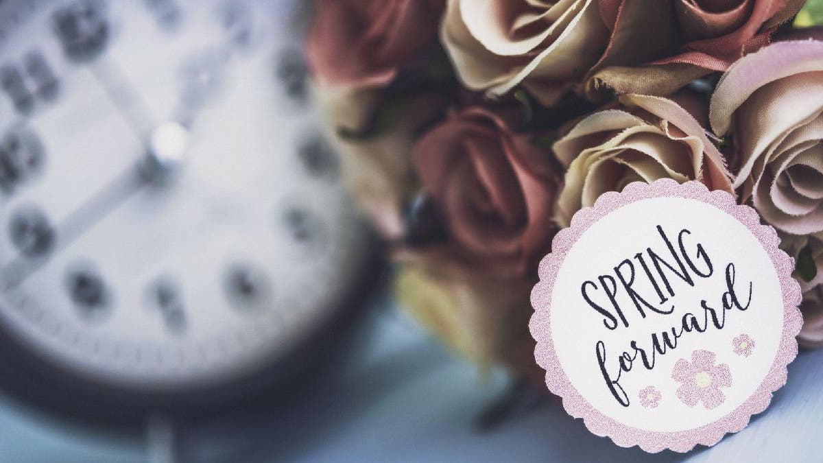 Daylight Saving Time clock with "spring forward" sign