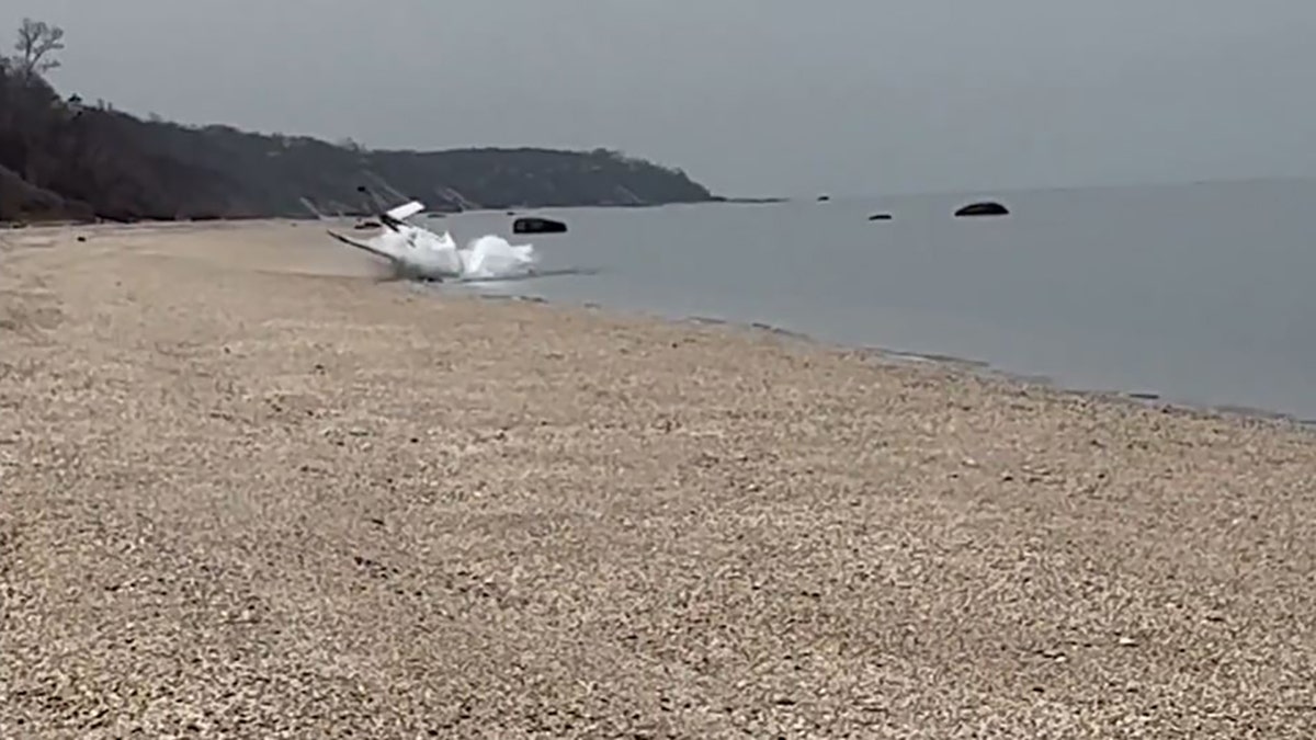 small plane sliding into water on shore of beach